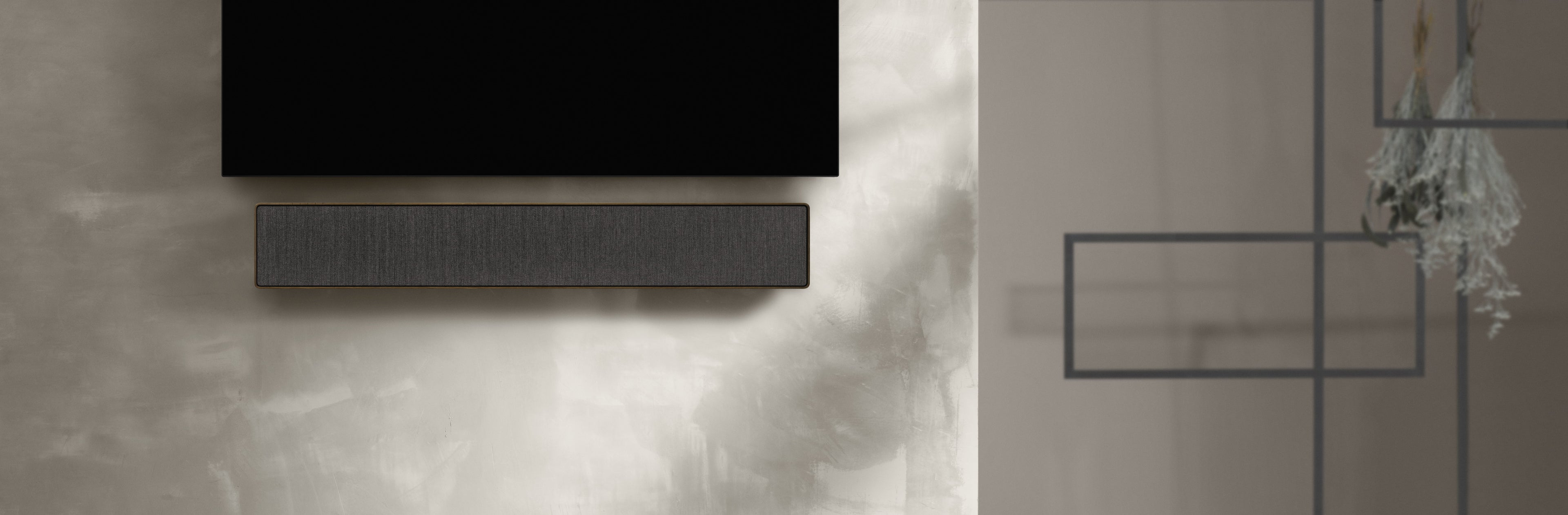 BeoSound Stage in Smoked oak an einer Wand unter einem Fernseher