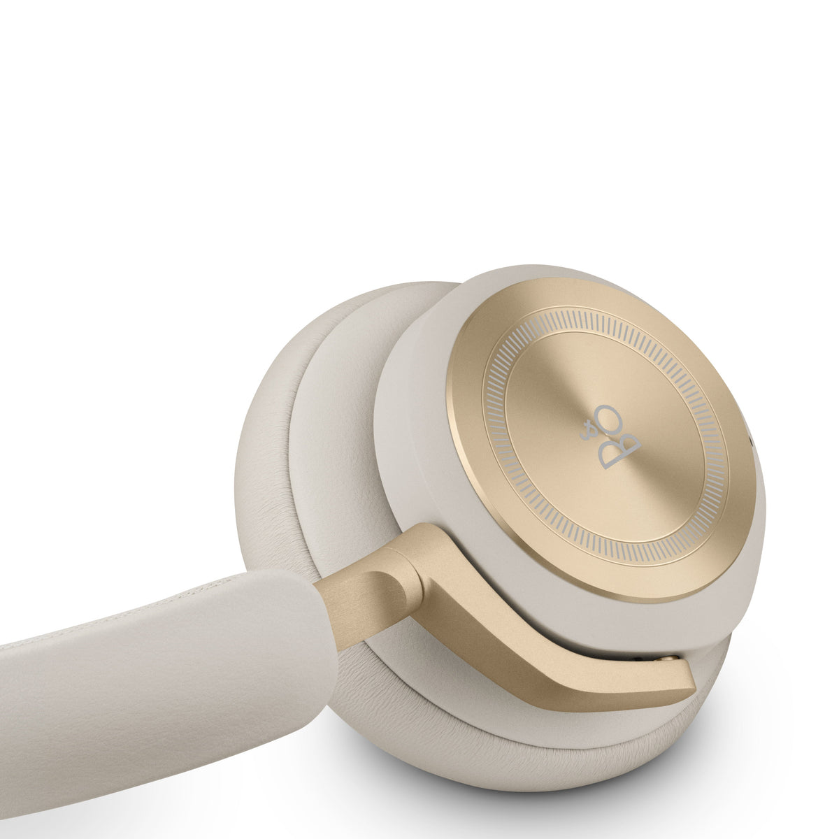 Nahaufnahme der Beoplay HX Kopfhörer. Sichtbar sind die weichen Lammleder-Ohrpolster, der sandfarbene Textil-Kopfbügel und der goldfarbene Aluminium-Gelenkarm. Fokus auf die exzellente Materialverarbeitung.