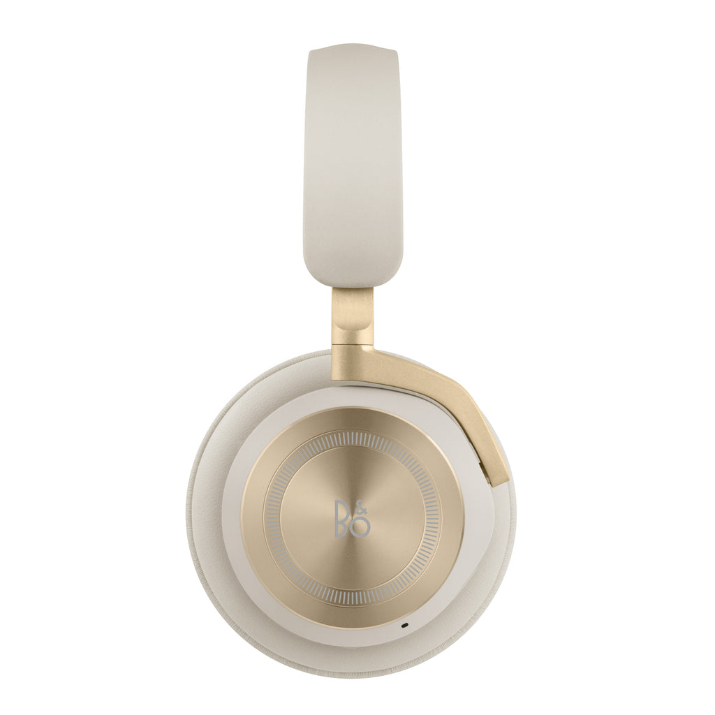 Studio-Aufnahme der Beoplay HX (Gold Tone) von der linken Seite. Die kreisförmige Aluminium-Oberfläche mit dem ikonischen B&O-Logo und dem feinen konzentrischen Muster steht im Fokus. Freigestellt auf Weiß.