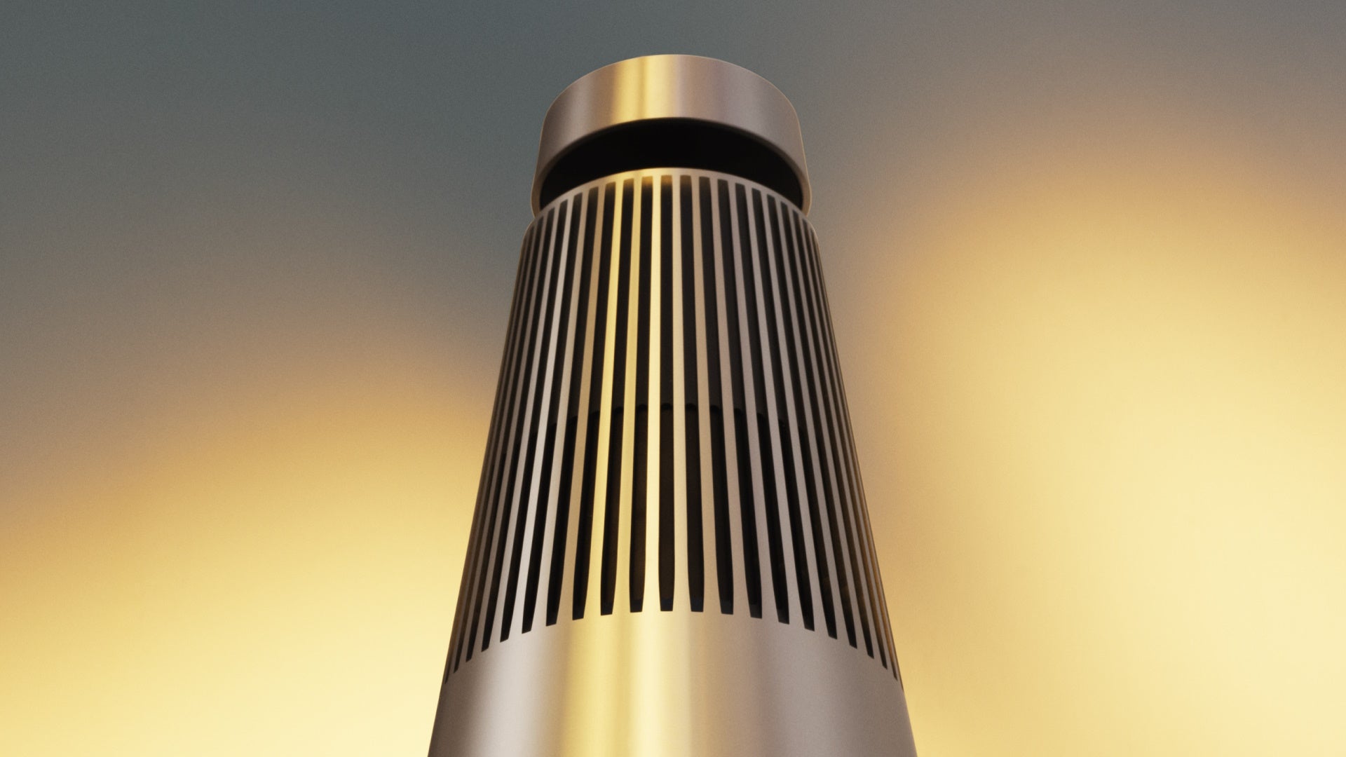 Dramatische Nahaufnahme des Bang & Olufsen Beosound 2 Lautsprechers in Gold Tone aus einer tiefen Froschperspektive. Die Ansicht betont die vertikale Lamellenstruktur und die konische Form vor einem sanften, farbverlaufenden Hintergrund in Gold- und Grautönen