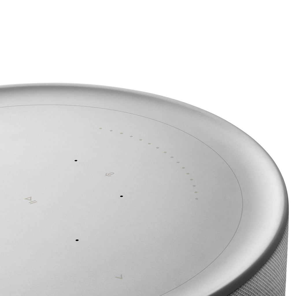 Nahaufnahme der interaktiven Oberseite der Beosound Balance. Die Touch-Oberfläche aus Glas zeigt die beleuchteten Bedienelemente für Wiedergabe, Bluetooth und Favoriten sowie den kreisförmigen Lautstärkeregler.