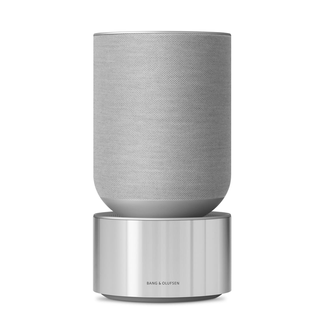 Studio-Aufnahme der Beosound Balance in Natural Aluminium / Grey Mist. Der Lautsprecher thront auf einer massiven, zylindrischen Aluminiumbasis, kombiniert mit einem nahtlosen Textil-Oberteil.